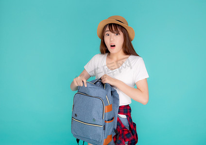 展架暑假招生摄影照片_美丽的肖像年轻亚洲女人戴着帽子打开背包和惊喜旅行暑假假期孤立在蓝色背景下，旅游女孩兴奋和震惊有包。