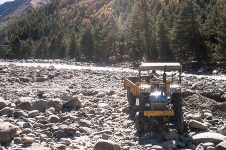 自主翻斗车施工车停在印度 Manali Beas 河岸的工业现场，有山地背景，用于建造加固河床的混凝土墙。