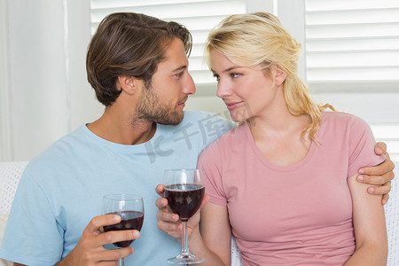 幸福的夫妻在沙发上一起喝红酒