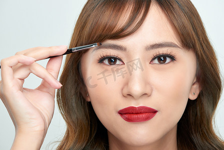 亚洲年轻美女在眉毛、自然妆、美颜上涂化妆粉刷