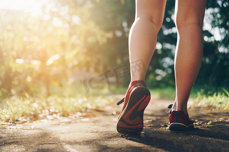 女人穿跑鞋在自然绿色背景下行走和跑步。健康锻炼。