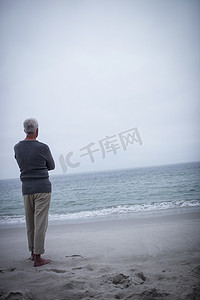 站在沙滩上的老人背面图