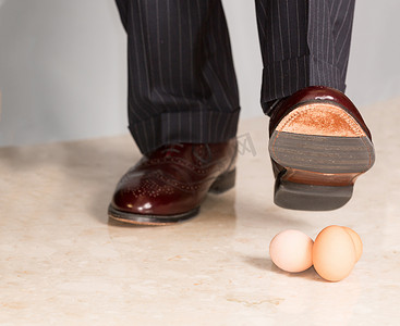 男人的鞋子踩在三个鸡蛋上