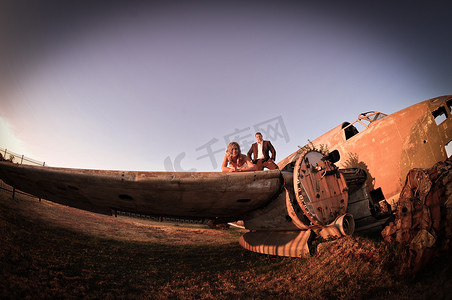 年轻的新婚夫妇站在坠毁的达科他州旧战机前