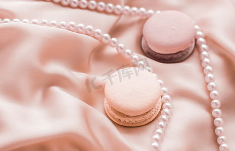 丝绸珠宝摄影照片_丝绸背景上的甜马卡龙和珍珠首饰、巴黎别致的珠宝、法式甜点食品和豪华糖果品牌的蛋糕马卡龙、节日礼物