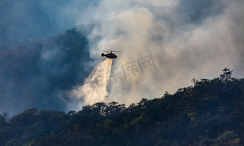 中火摄影照片_直升机在森林火灾中倾倒水