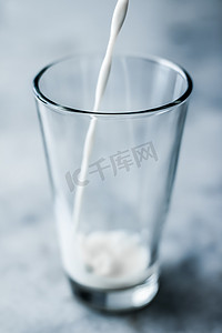 世界食物日摄影照片_世界牛奶日，倒入大理石桌上的玻璃杯中