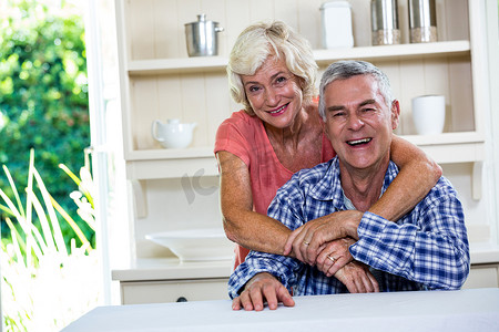 微笑的老夫妇在家里的厨房里拥抱
