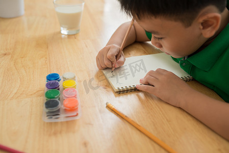 可爱的男孩做作业、涂色、写作和绘画。