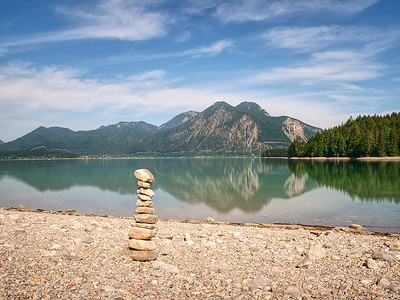 鹅卵石湖滩上的扁平石头金字塔，地平线上的群山