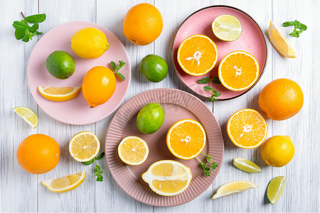 柑橘类水果摄影照片_粉红色陶瓷板上整个和切好的柑橘类水果的特写