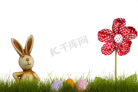 兔子粉色摄影照片_在草后的复活节兔子与帷幔花和复活节彩蛋
