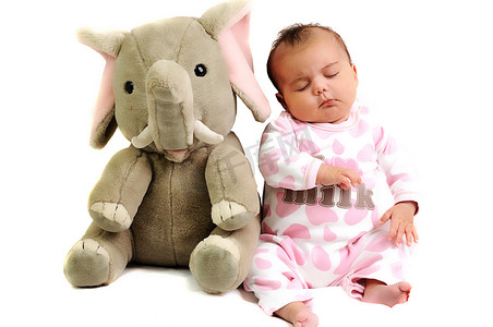 坐着睡觉的女婴，旁边放着大象玩具