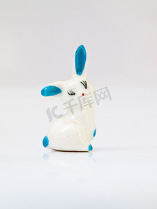 瓷娃娃摄影照片_白色兔子陶瓷娃娃，上面有淡蓝色斑点