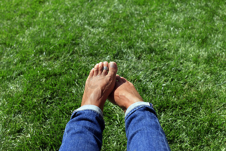 赤脚在绿草中，女人在大自然中放松