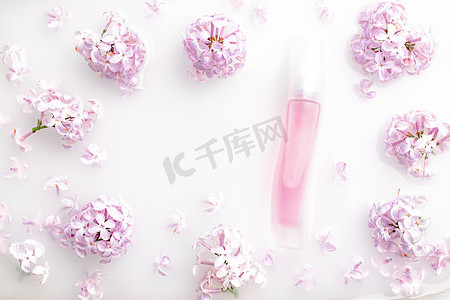 粉红色香水瓶和白色背景上的淡紫色分支。