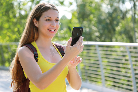 微笑的女性徒步旅行者用智能手机检查 GPS 坐标以寻找正确方向的画像。
