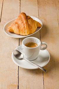 咖啡灌摄影照片_木桌上的咖啡和羊角面包