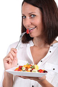 平衡膳食摄影照片_吃水果沙拉的中年妇女