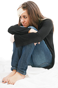 悲伤的女孩少年坐着双臂缠绕在腿上。