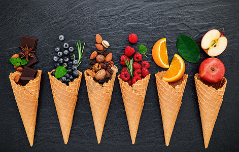 在黑石背景上设置的各种冰淇淋口味成分，包括蓝莓、酸橙、开心果、杏仁、橙子、巧克力、香草和咖啡。