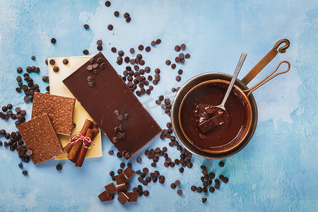 铜锅里融化的巧克力，质朴的蓝色表面旁边是黑巧克力和白巧克力
