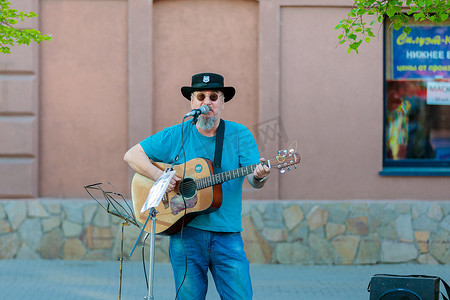 一个头发花白的成年男子在城市街道上弹吉他唱歌。