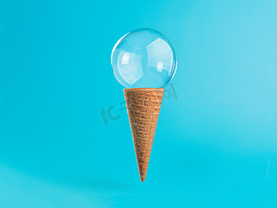 蓝色背景的图摄影照片_蓝色背景中带肥皂泡的冰淇淋锥