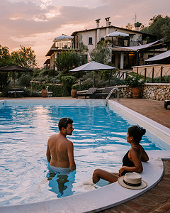 日落真实摄影照片_意大利带游泳池的豪华乡间别墅，意大利豪华别墅度假的情侣，男人和女人看日落