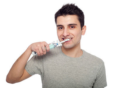 电动牙刷摄影照片_刷牙的年轻人