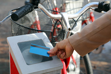 女手用信用卡支付自行车费用，在室外租赁站使用现代非接触式系统