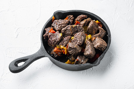 胡萝卜土豆摄影照片_用土豆、胡萝卜和香料炖牛肉，用铸铁煎锅，白石表面