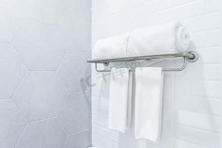 酒店浴室摄影照片_干净的毛巾与墙上浴室内部背景上的衣架。