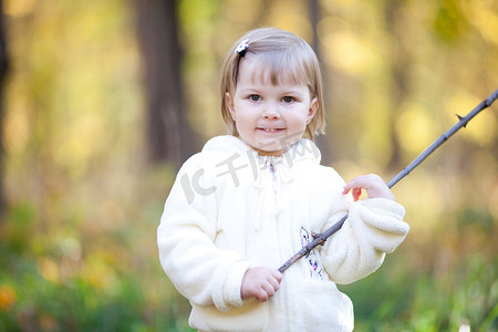秋天的森林里拿着棍子的漂亮小女孩