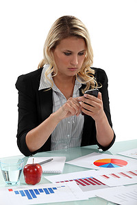 一位女商人在办公桌上用图表发短信。
