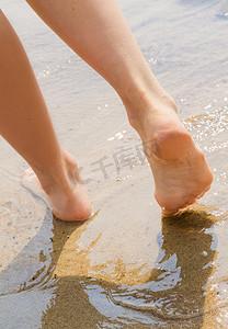 年轻女子在潮湿的海边散步
