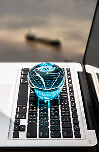 阳台和河景笔记本电脑键盘上的玻璃水晶蓝苹果。