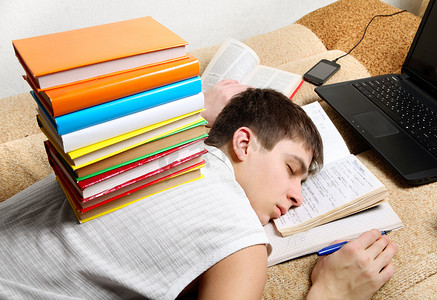 青少年低度近视摄影照片_疲倦的少年在学习后睡觉