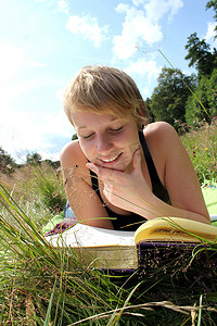 夏天教育摄影照片_女孩正在夏天的草地上读书