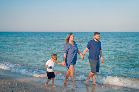 孩子爸爸妈妈摄影照片_爸爸妈妈和孩子一起度过家庭假期父母爸爸妈妈和儿子一起散步享受海滩