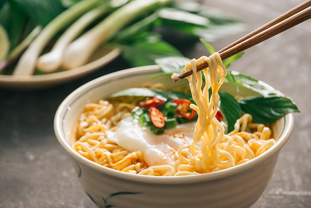 在 dảk 石头背景、垃圾食品或快餐概念上用筷子上的蔬菜封闭方便面。