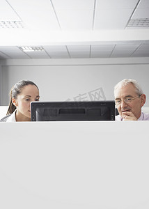 严肃的女商人和商人在隔间里看电脑