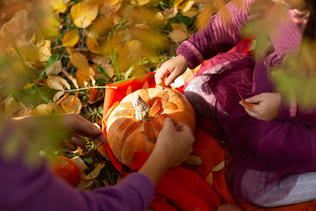秋天公园里可爱的小女孩，有橙色的叶子和黄色的南瓜。