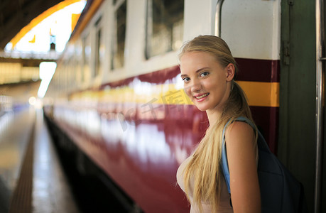 老式火车摄影照片_年轻女子在老式火车上等车，在泰国曼谷的车站月台上放松而无忧无虑，然后才赶上火车。