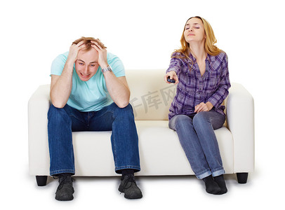 坐在沙发上的父亲摄影照片_紧张的丈夫和妻子坐在沙发上看电视