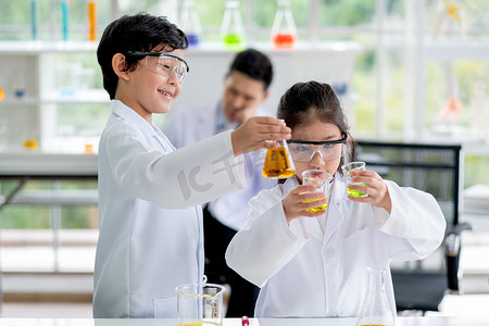 小男孩和女孩科学家喜欢通过女孩比较化学品的颜色来检查实验室中的颜色化学品。