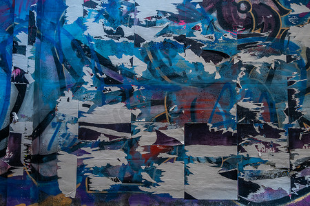 垃圾旧墙上的彩色撕破海报作为创意和抽象背景