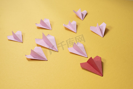 黄色背景中红色纸飞机后的一组粉红色纸飞机折纸