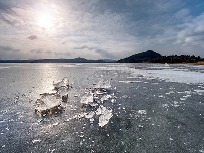 结冰的湖摄影照片_结冰的湖面上破碎的厚冰在阳光下闪闪发光。