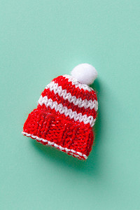 条纹小针织冬季无檐小便帽，绿松石背景上有绒球。